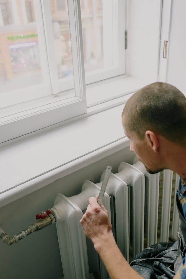 Artisan travaillant près d'un radiateur avec une règle
